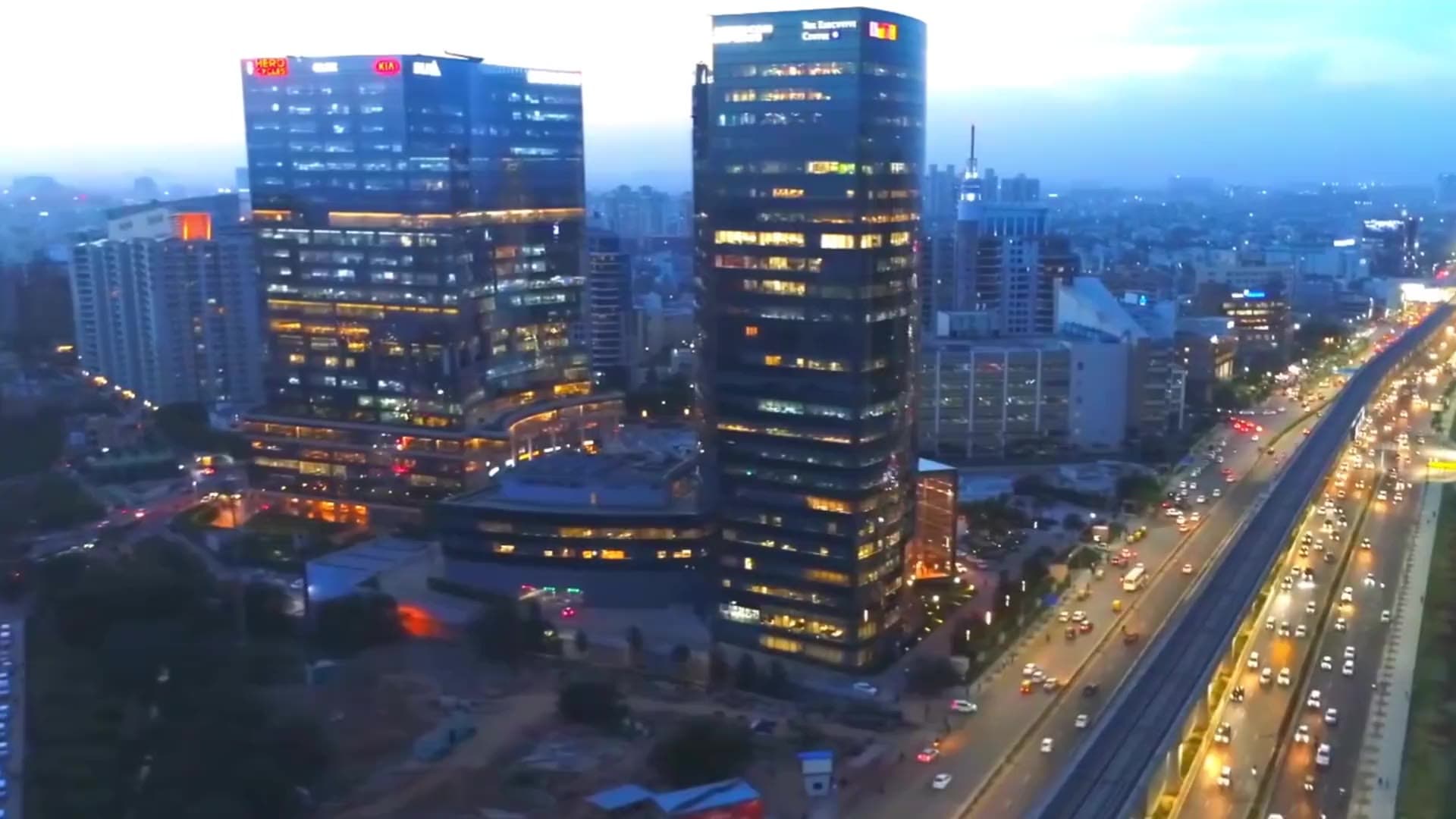 Aerial view of Gurugram at dusk — glass towers and a busy, lit-up expressway